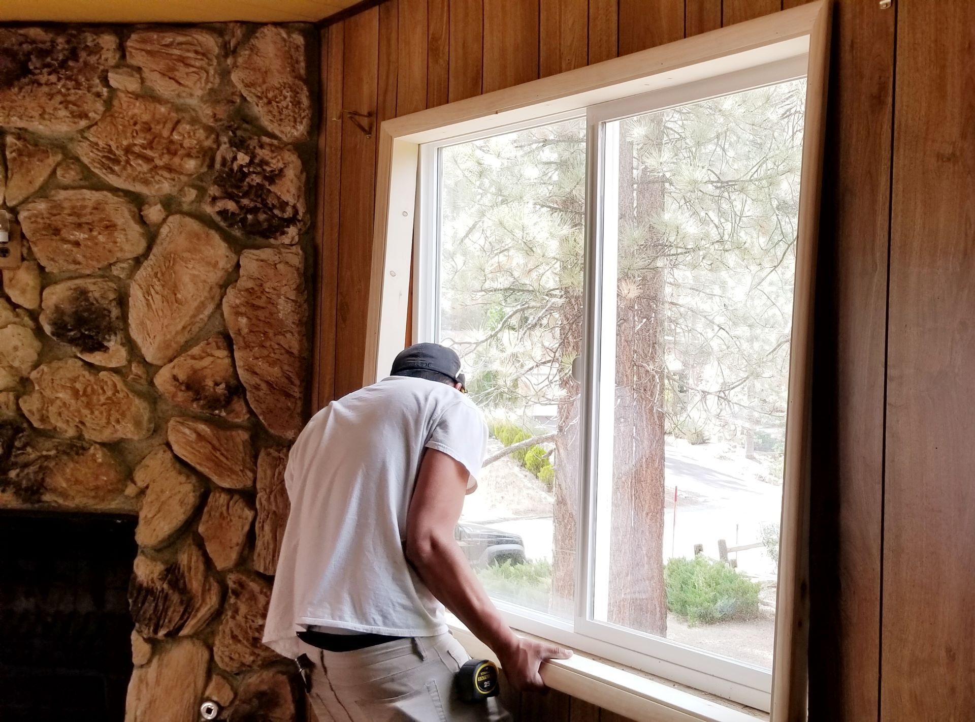 A window installer adds a new wood window sill and frame