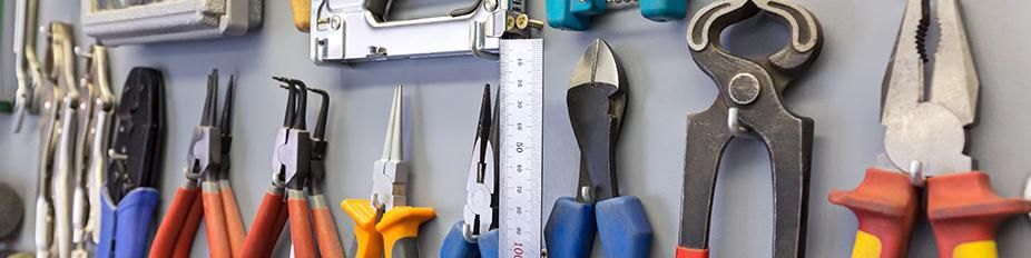 Herramientas, incluidos alicates y cortadores, colgadas en una pared.