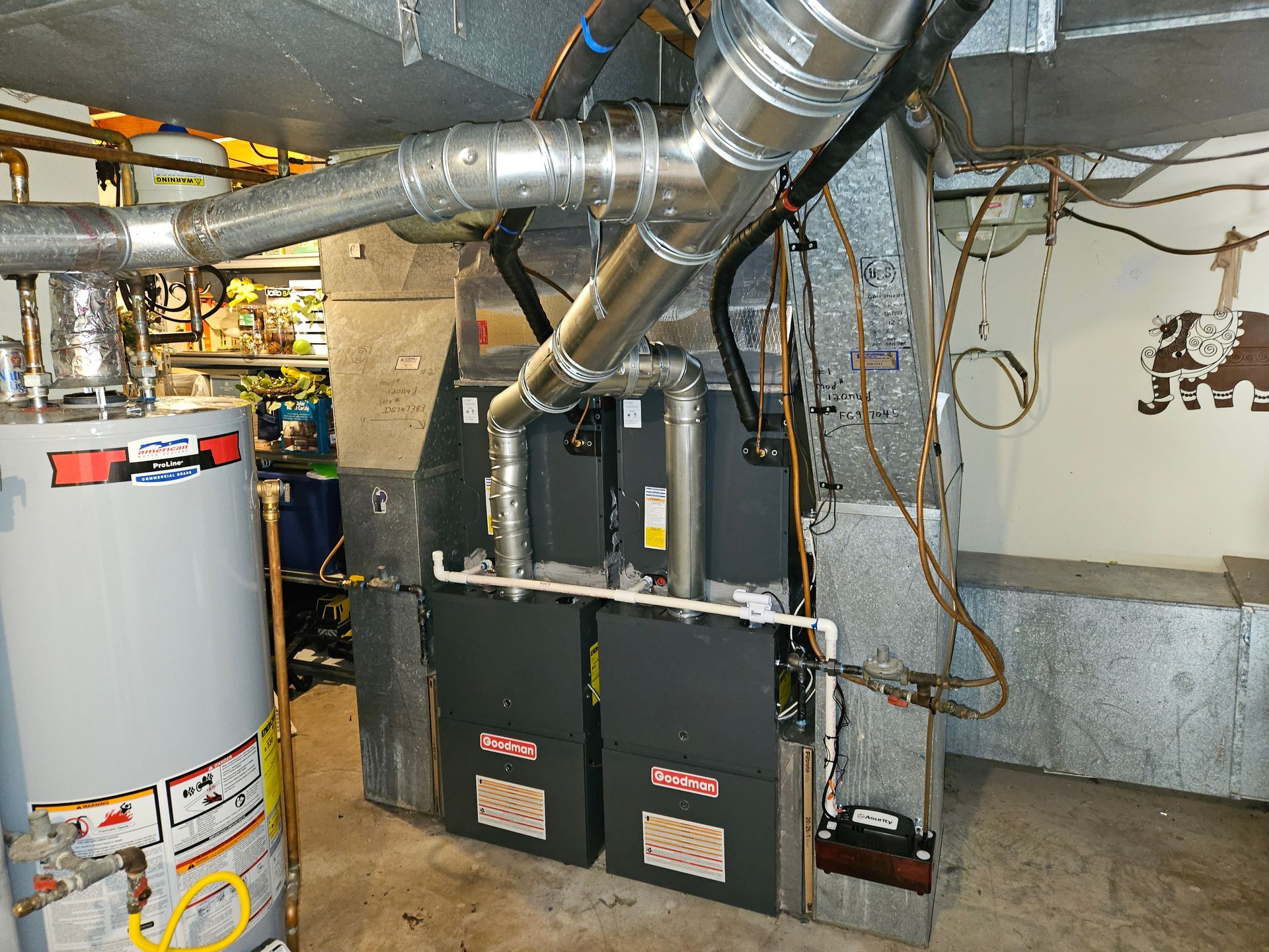 Furnace and water heater in a basement setting. Metal ducts and pipes are visible, along with the gray appliances.