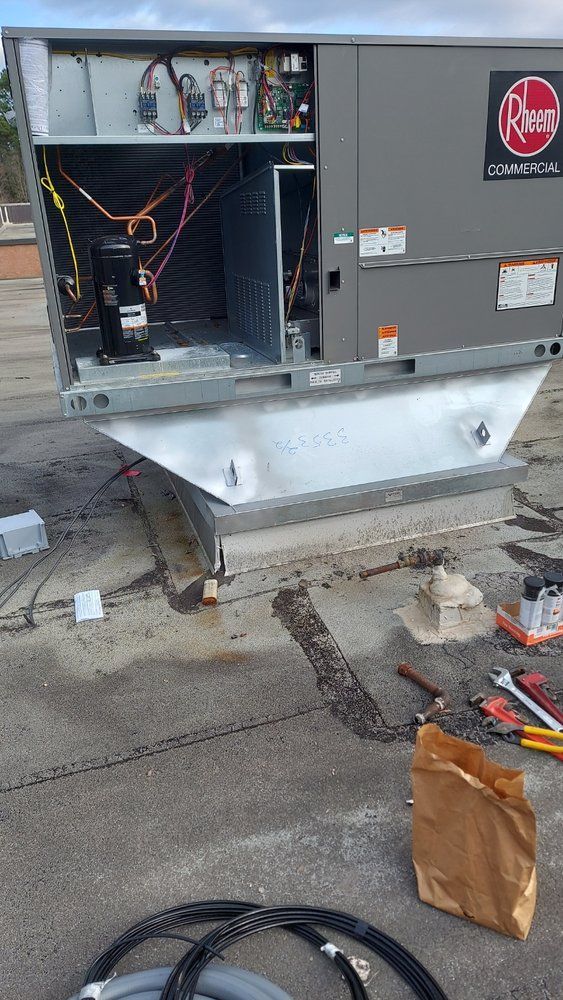 HVAC unit on a rooftop being worked on. The gray unit is open, revealing internal components