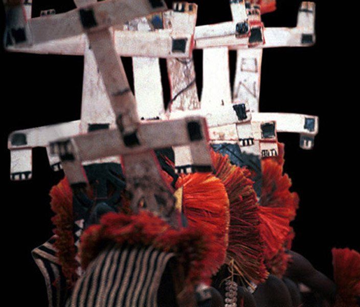 A person wearing a striped shirt and a feathered headdress