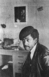 A black and white photo of a man wearing a hat and a leather jacket.