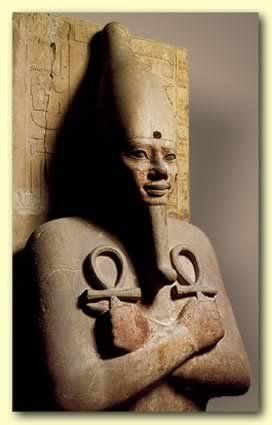 A statue of a man with a large head and ankh symbols on his chest.