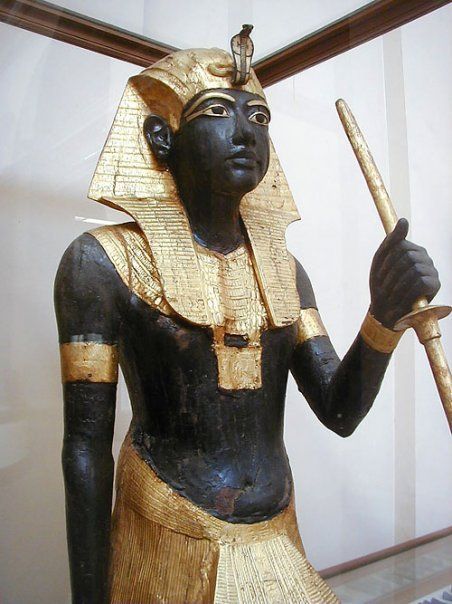 A black and gold statue of a pharaoh holding a staff