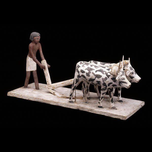 A statue of a man plowing with two cows pulling a plow
