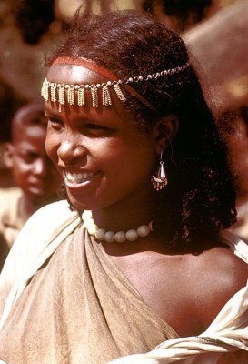 A woman wearing a headband and earrings is smiling.