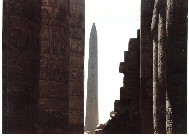 An obelisk is visible through the pillars of a building