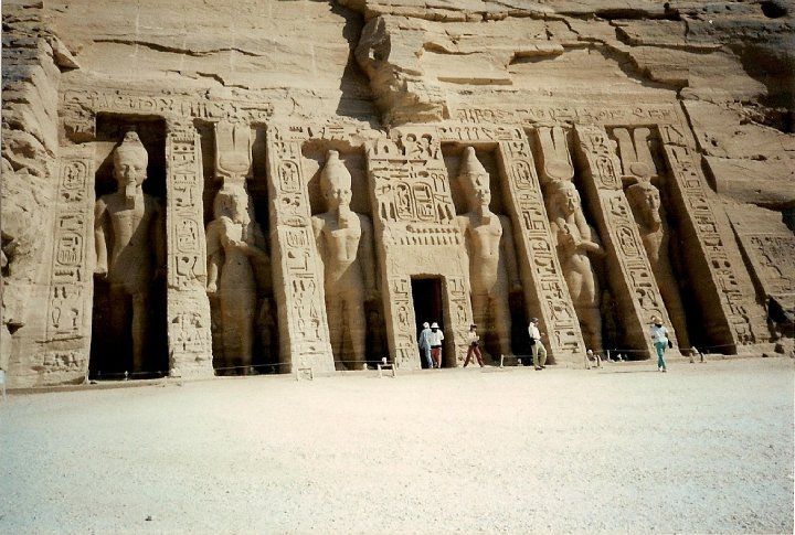 A group of people are standing in front of a large stone building