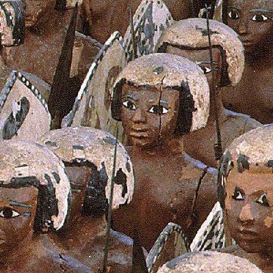 A group of wooden statues of people with shields on their heads.