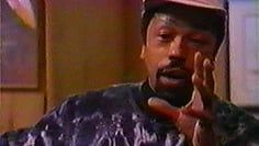 A man wearing a hat is making a peace sign with his hands.