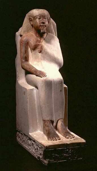 A statue of a man sitting in a chair on a black background.