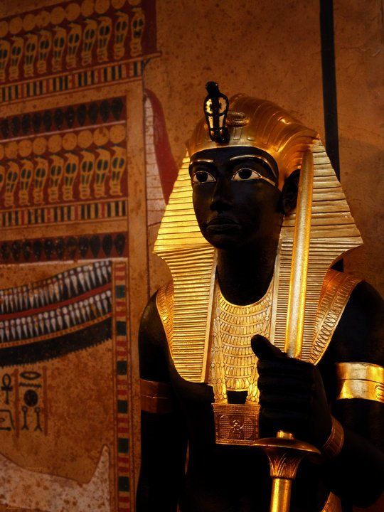 A statue of an ancient egyptian king holding a cane