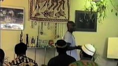 A group of people are sitting in a room with a man standing in front of them.