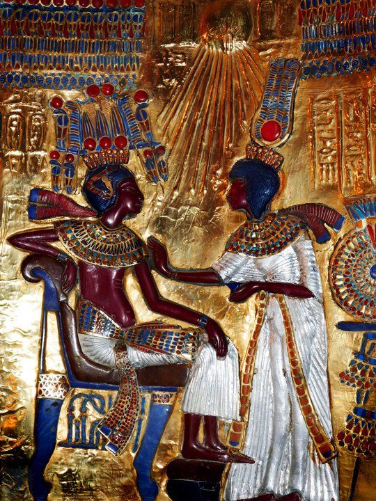 A statue of a man and woman sitting next to each other on a gold background.