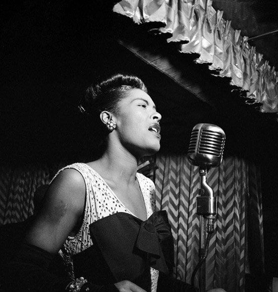 A black and white photo of a woman singing into a microphone