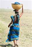A woman is carrying a bowl on her head.