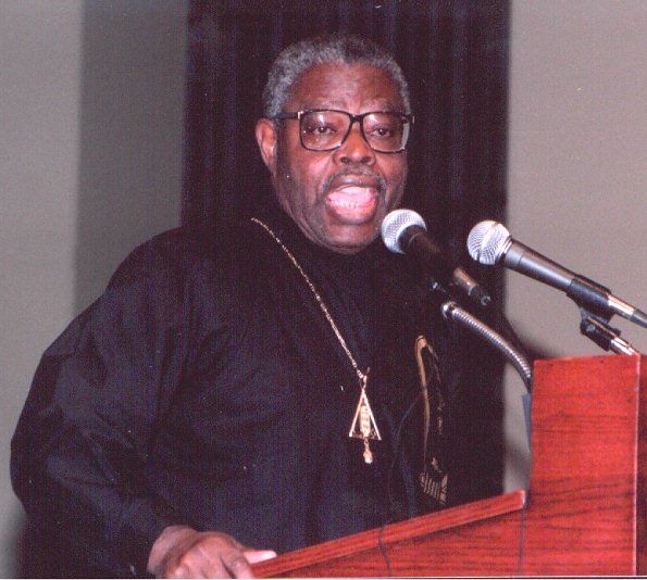 A man stands at a podium speaking into two microphones