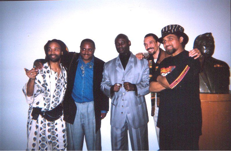 A group of men are posing for a picture with a statue in the background