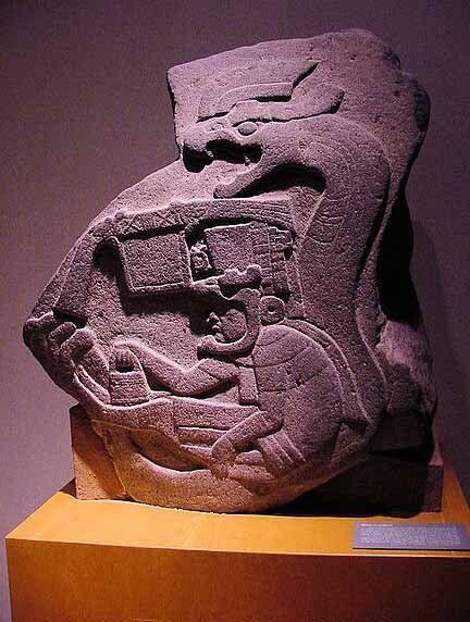 A statue of a man is sitting on a wooden pedestal.