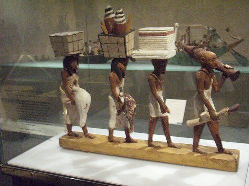 A statue of a group of people carrying boxes on their heads