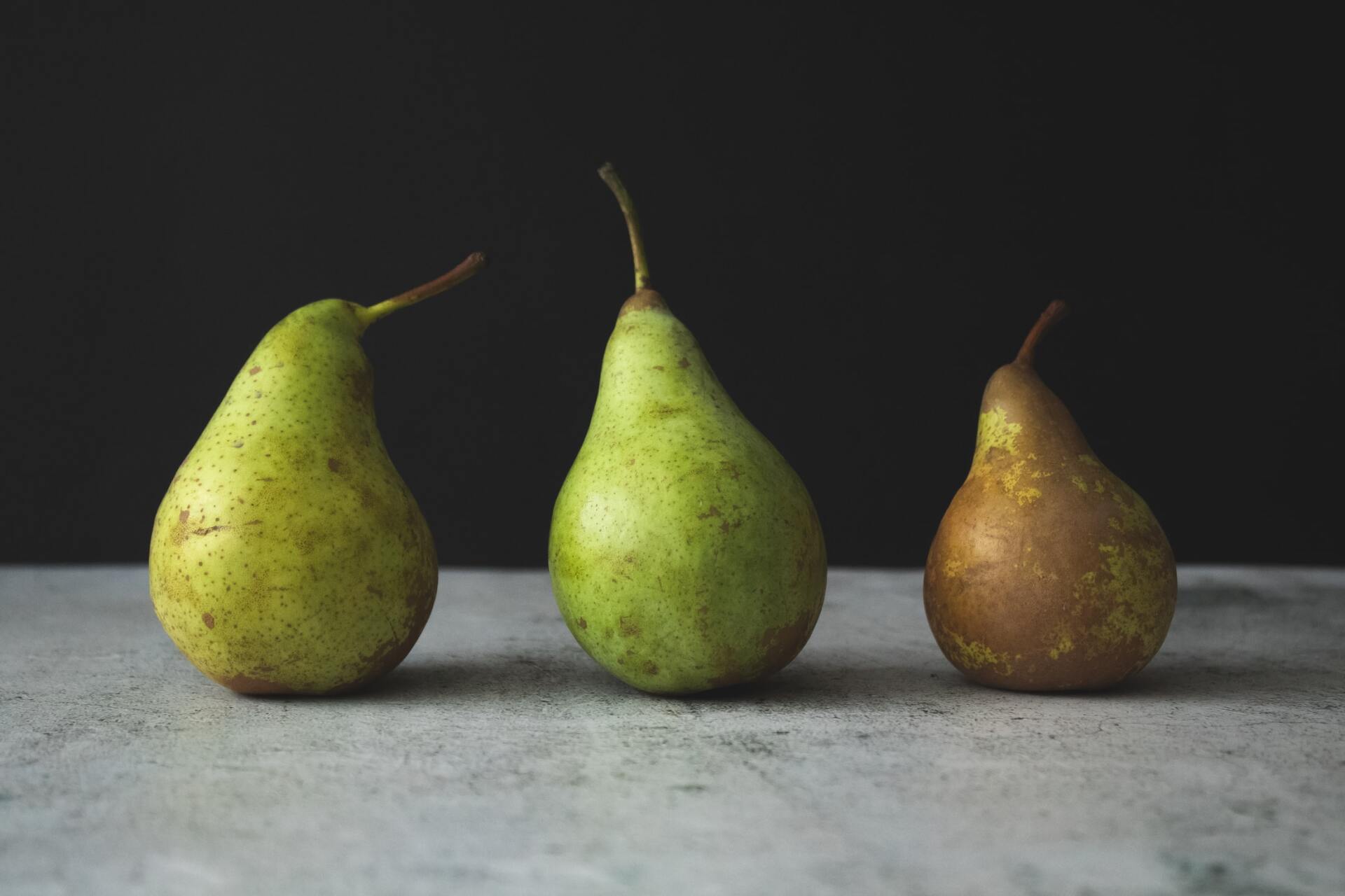 Three pears are sitting next to each other on a table.