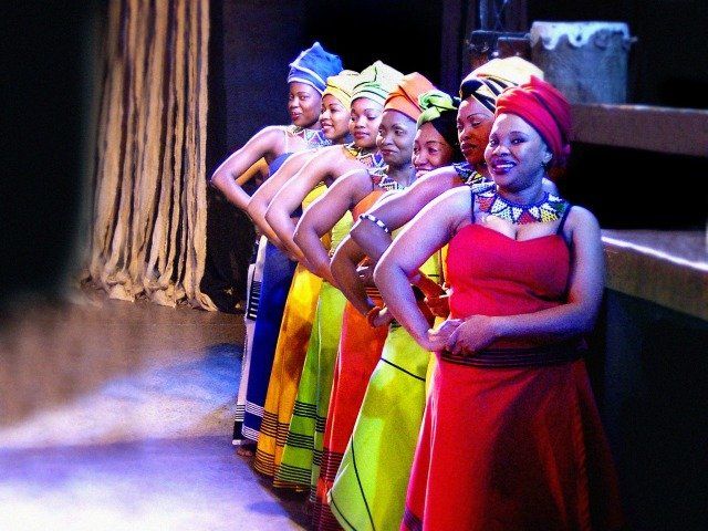 A group of women in colorful dresses are standing in a row