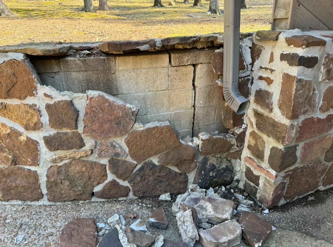 A brick wall with a hole in it and a drain pipe.