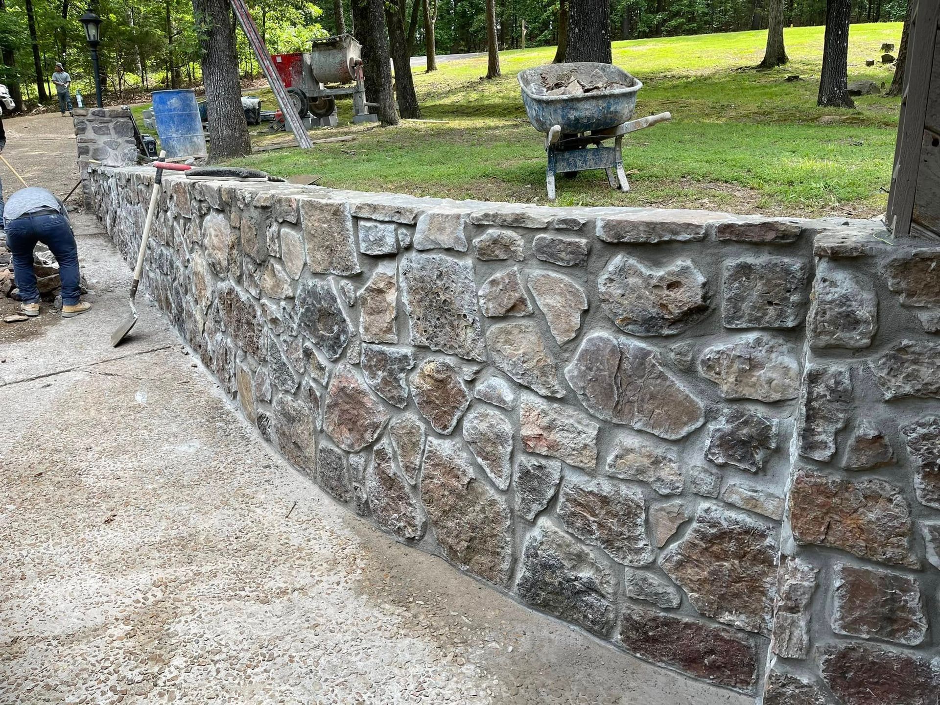 A man is working on a stone wall in a park.