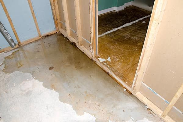 A room with a leak in the floor and a door.