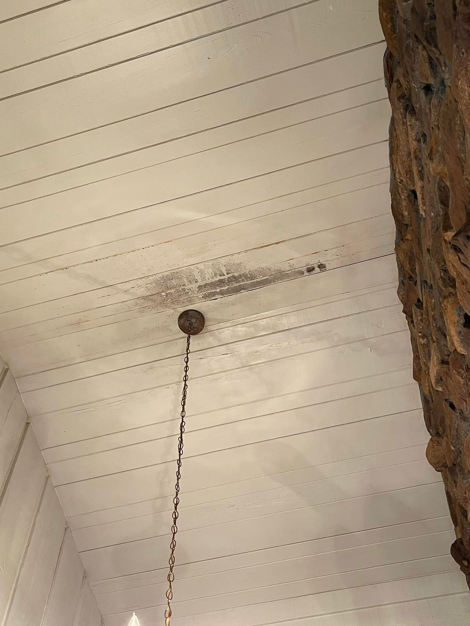 A ceiling fan is hanging from the ceiling of a room next to a stone wall.