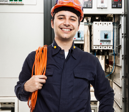 A man wearing a hard hat and goggles is holding an orange cable