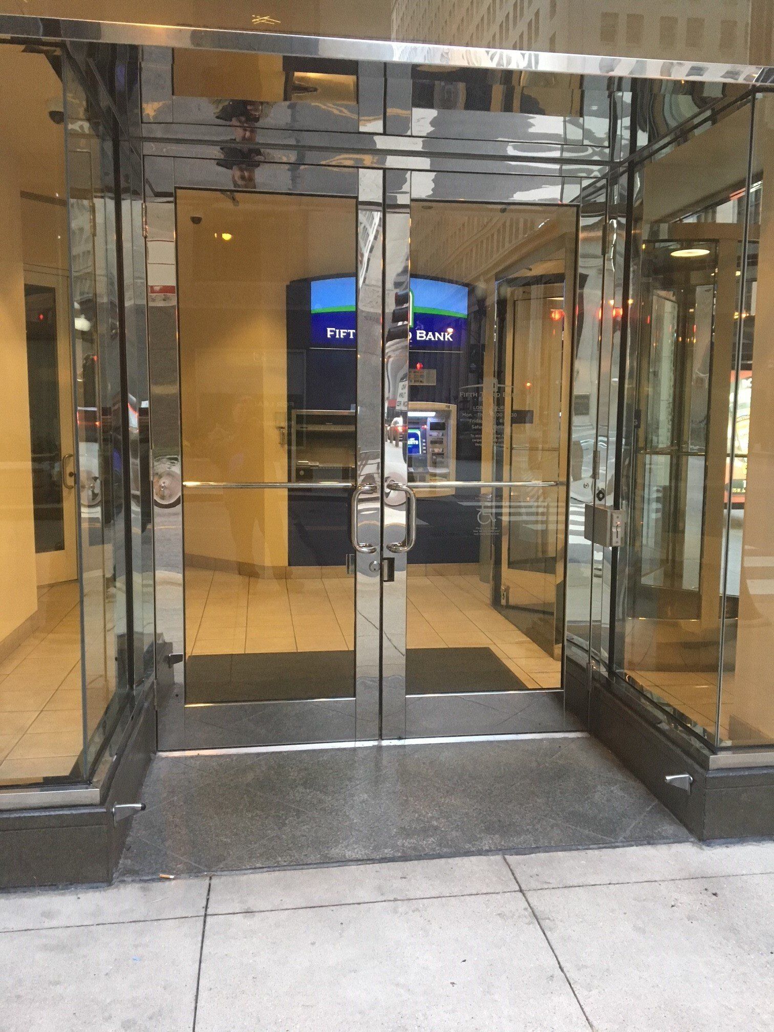 A glass entrance to a building with an atm in the background