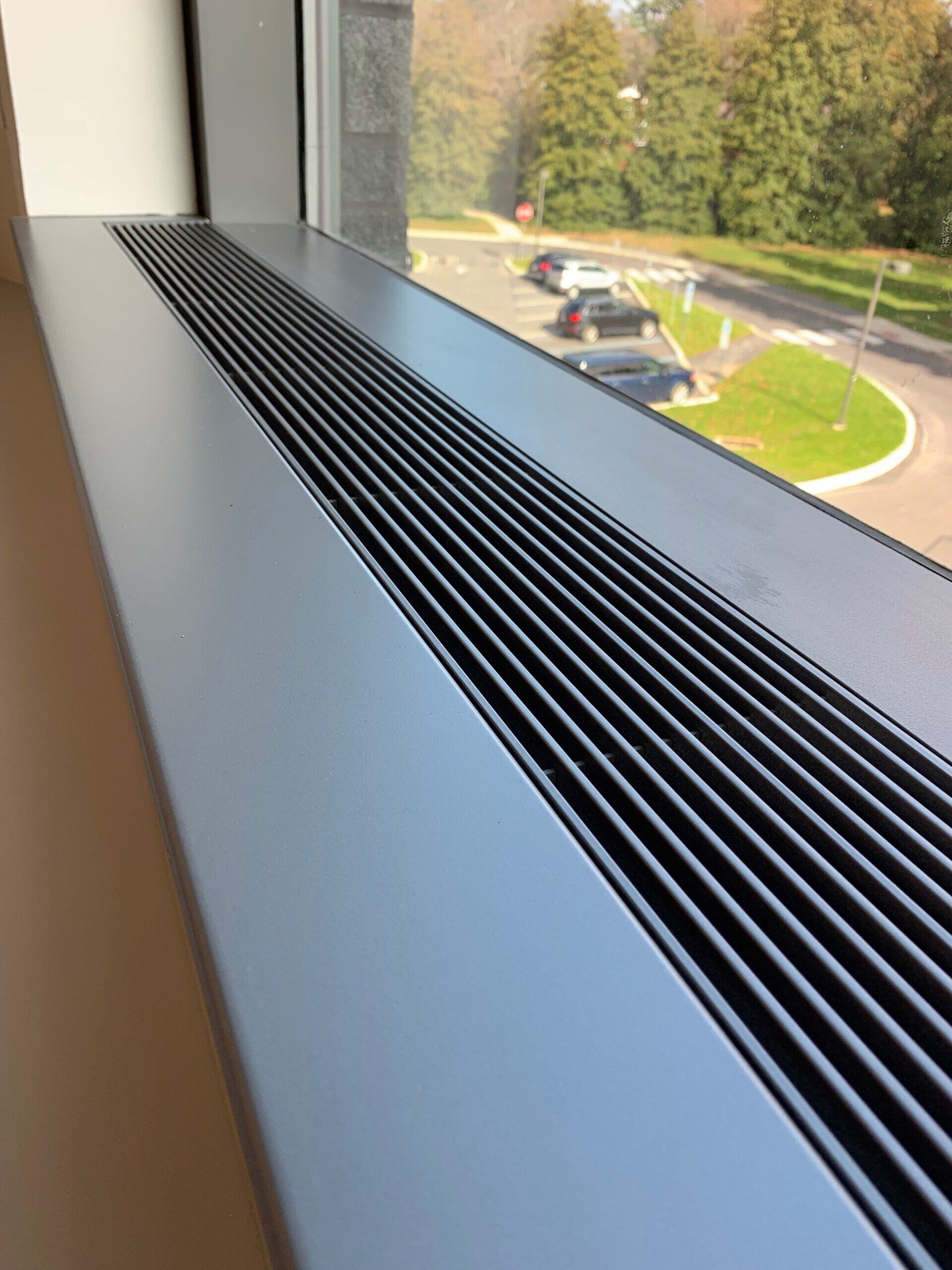 A close up of a window sill with a view of a parking lot.