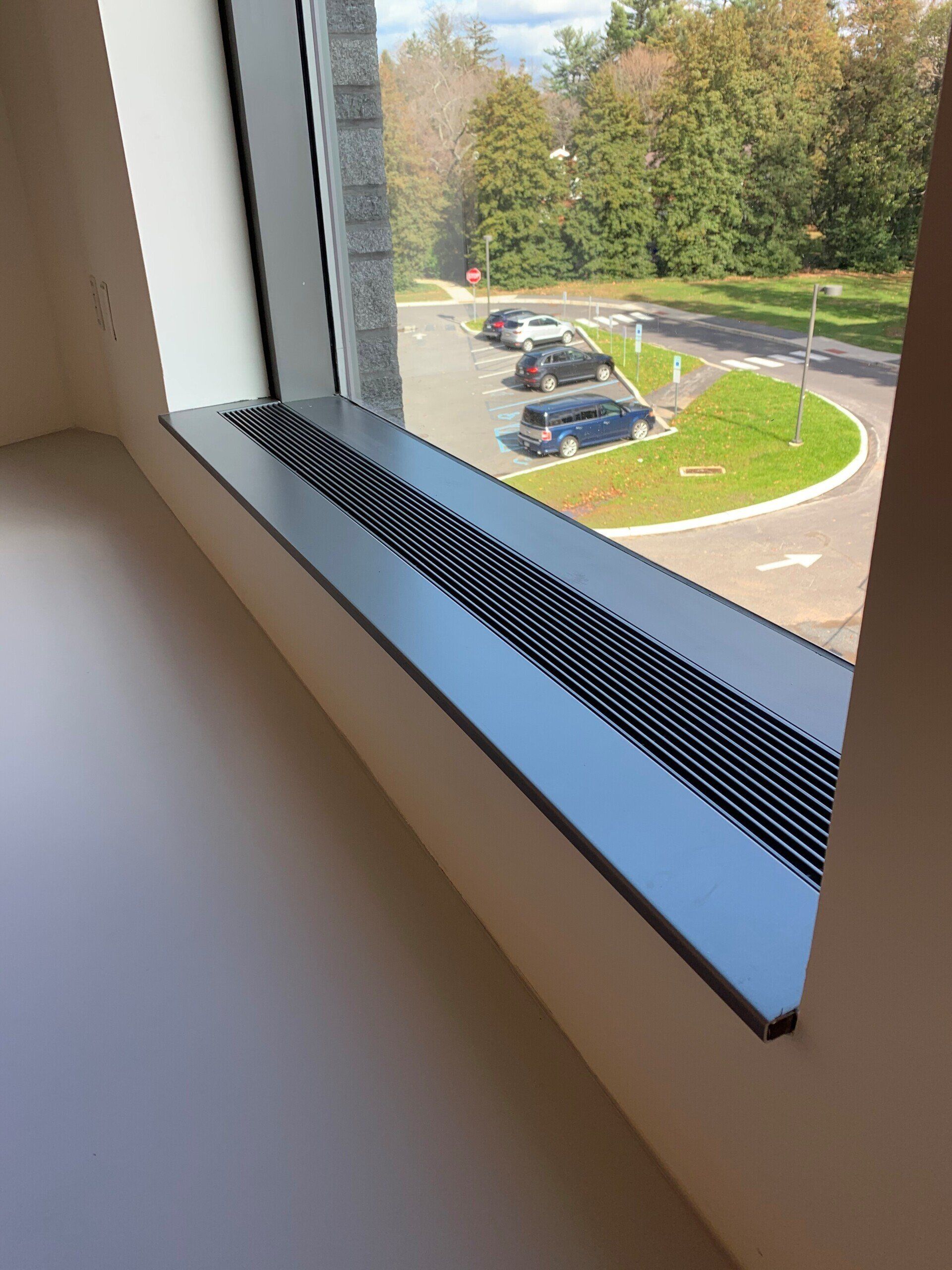 A window with a view of a parking lot and trees