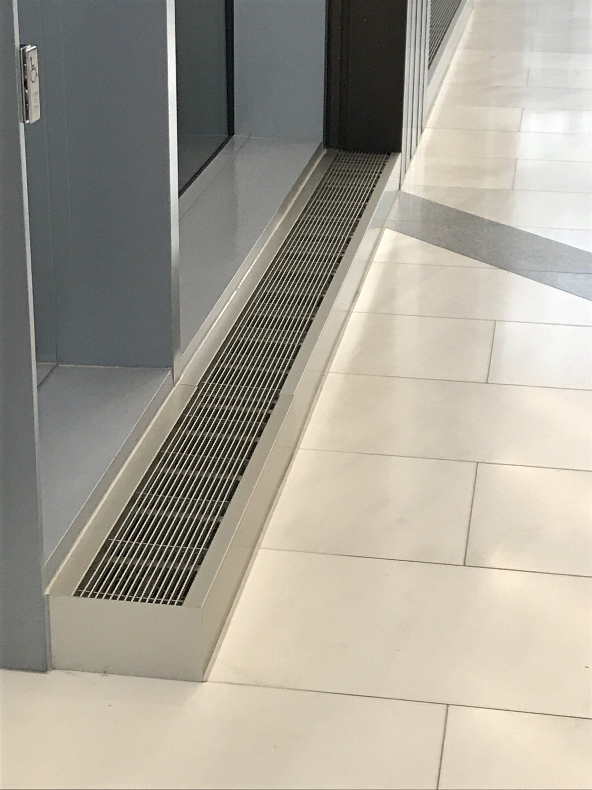 A hallway with a drain on the floor next to a door.