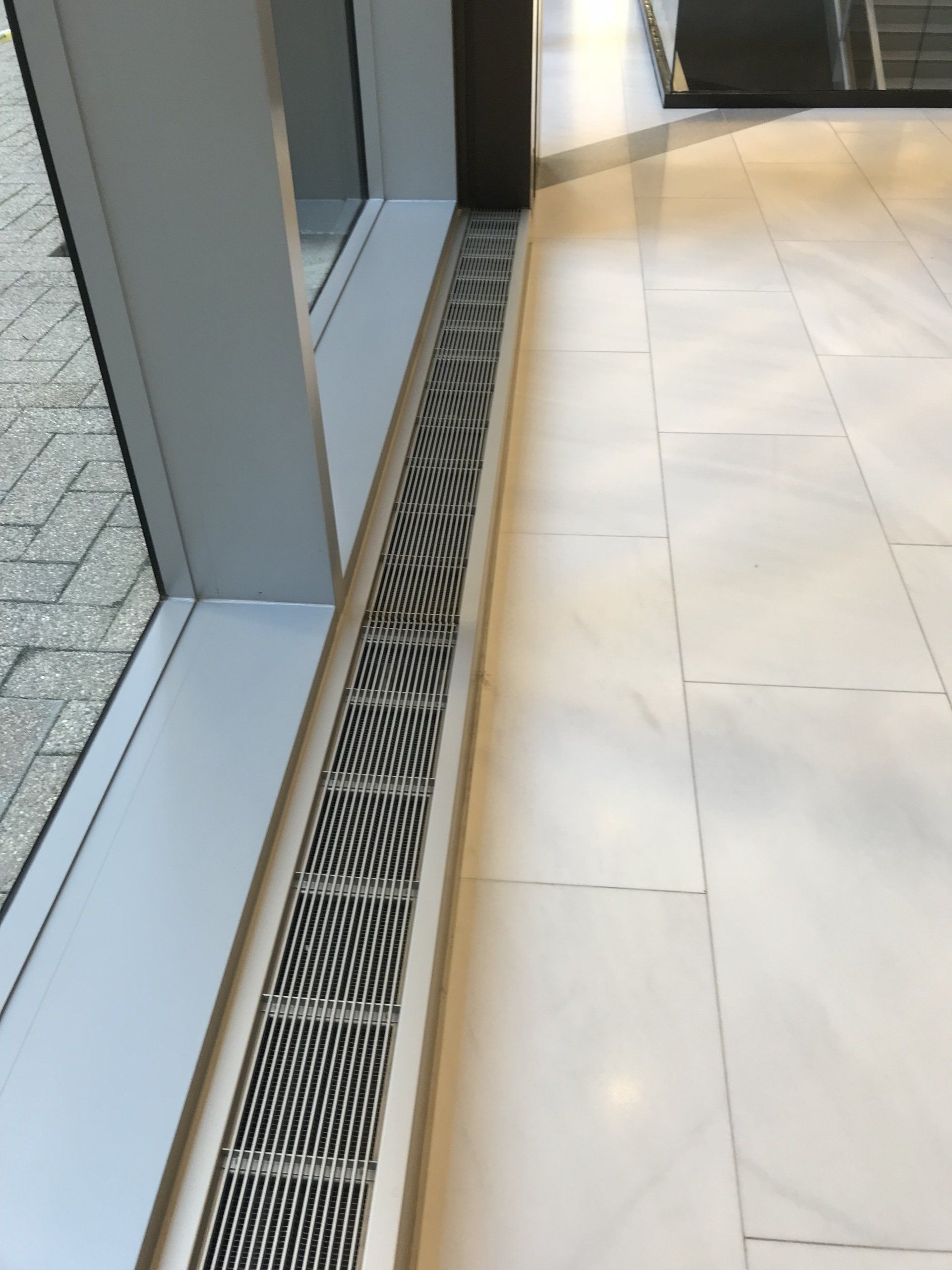 A drain on the floor next to a window in a building