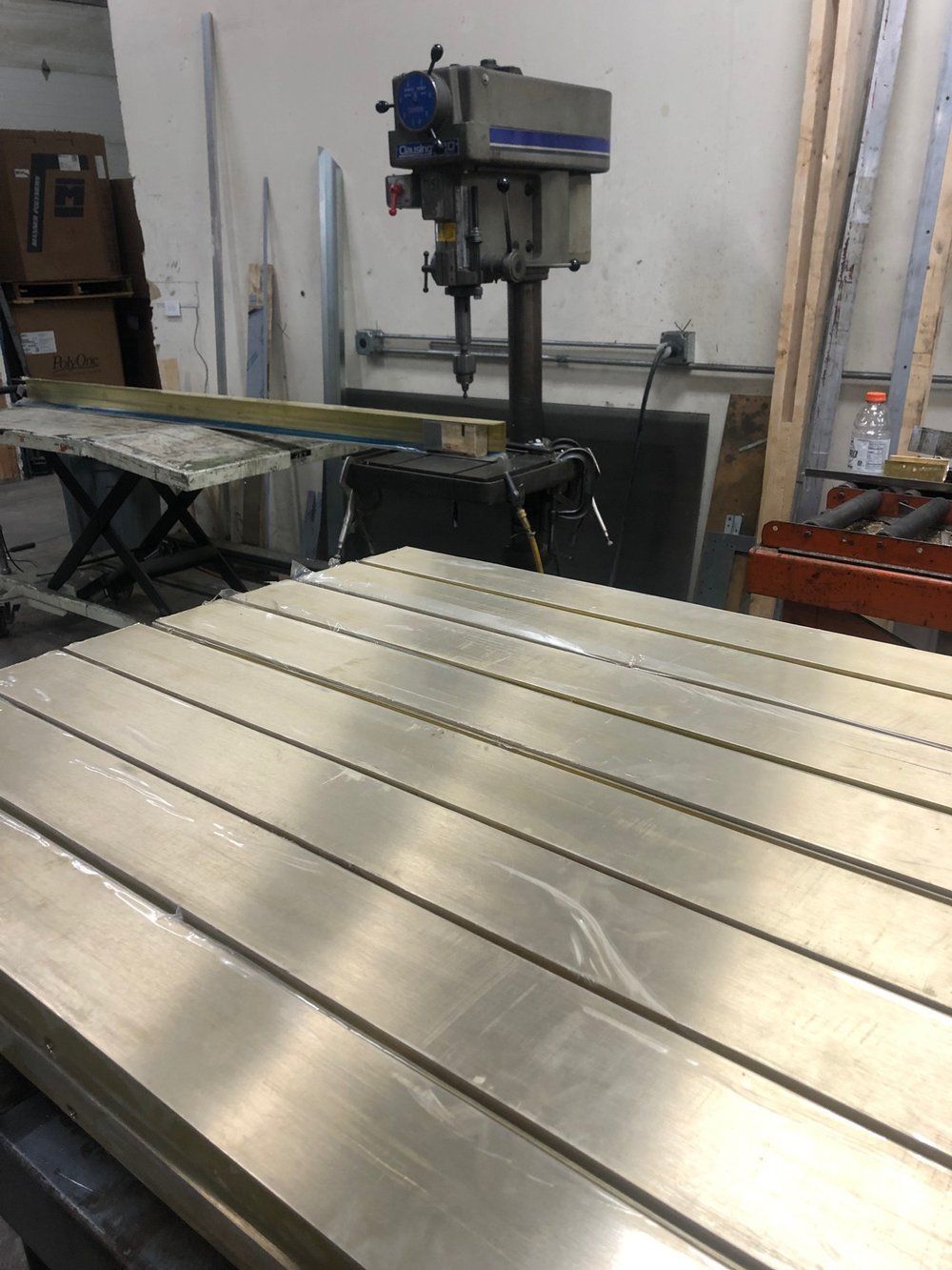 A drill is sitting on top of a metal table in a workshop.