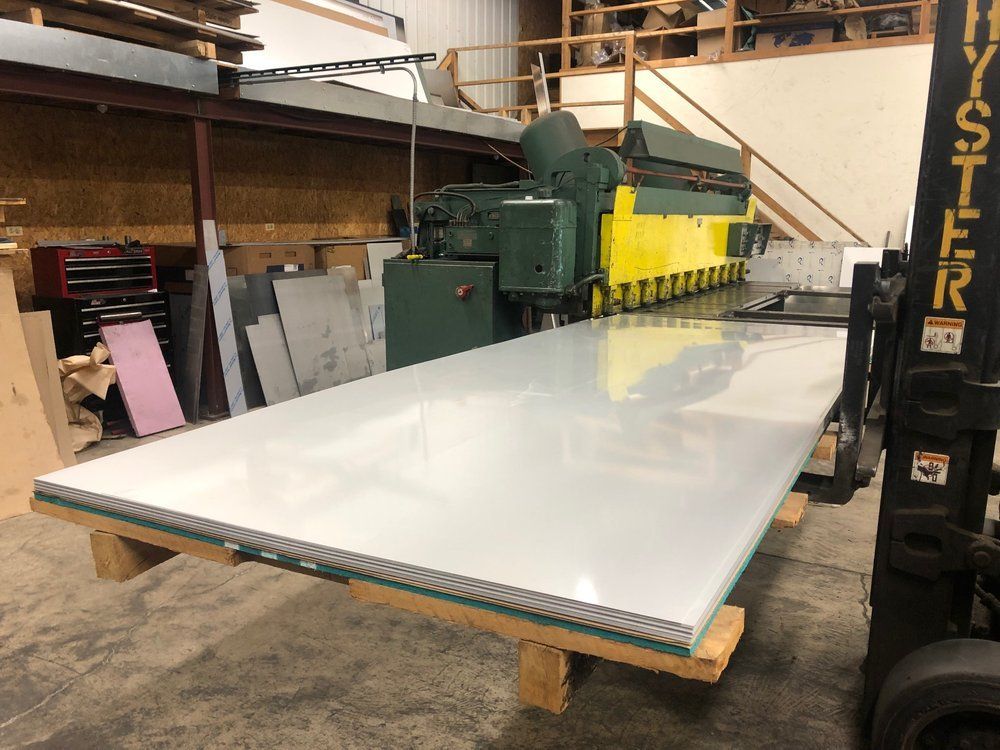 A forklift is carrying a large piece of metal in a warehouse.