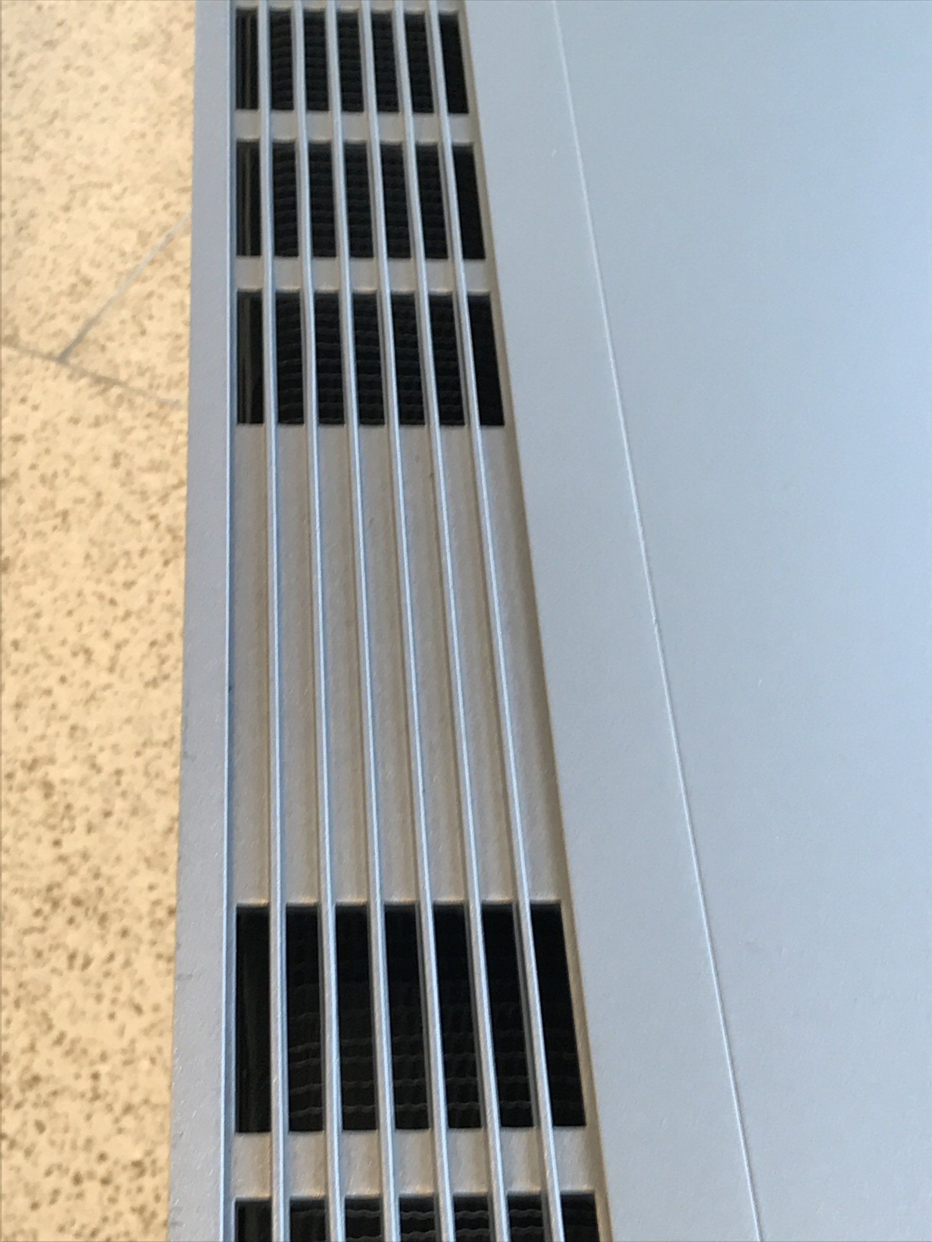 A close up of a metal grille on a white surface