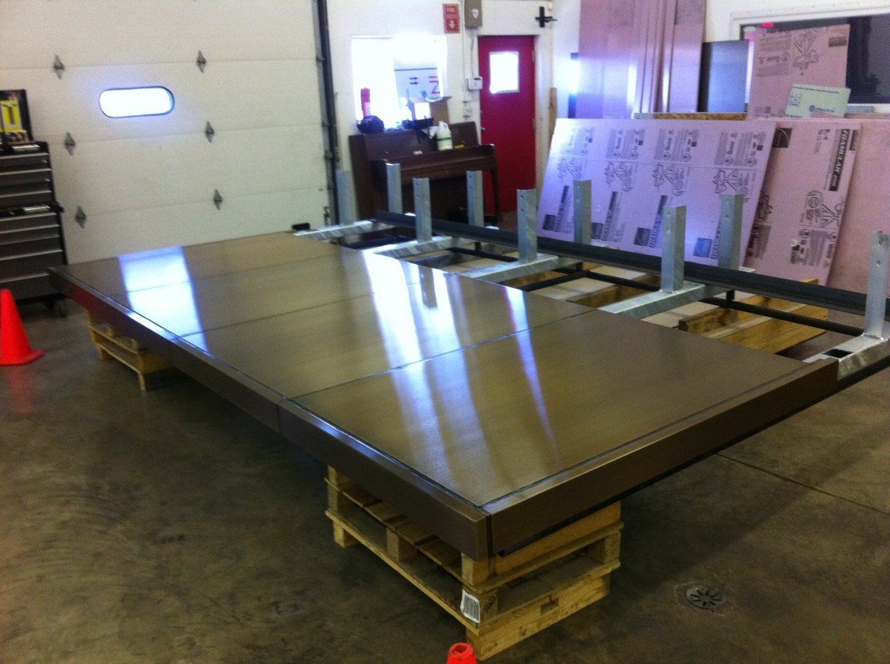 A large stainless steel table is sitting on a wooden pallet