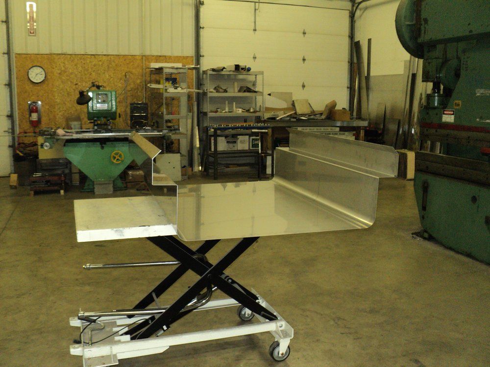 A stainless steel table is sitting on a cart in a workshop