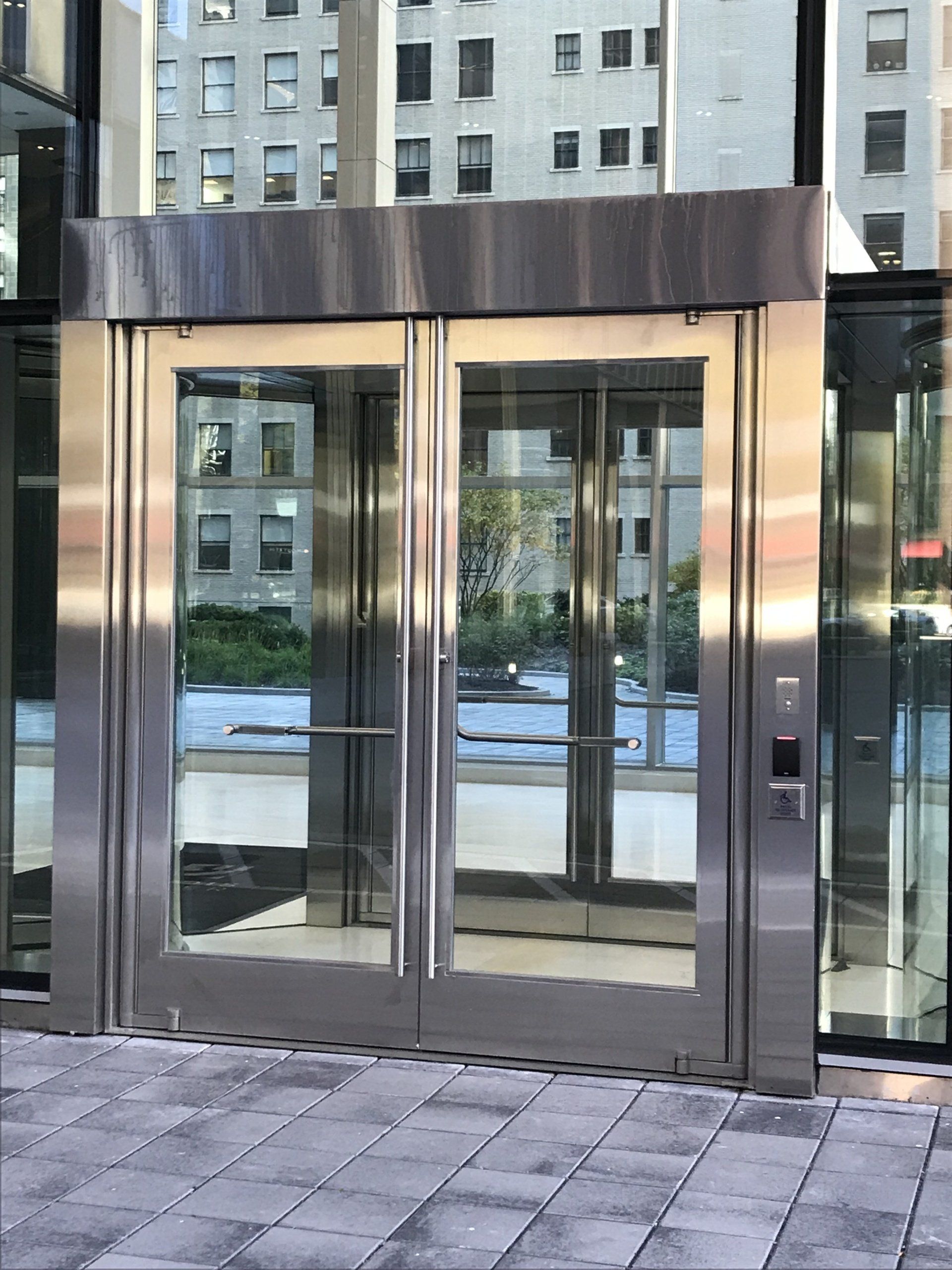 A stainless steel door with glass panels is open to a building.