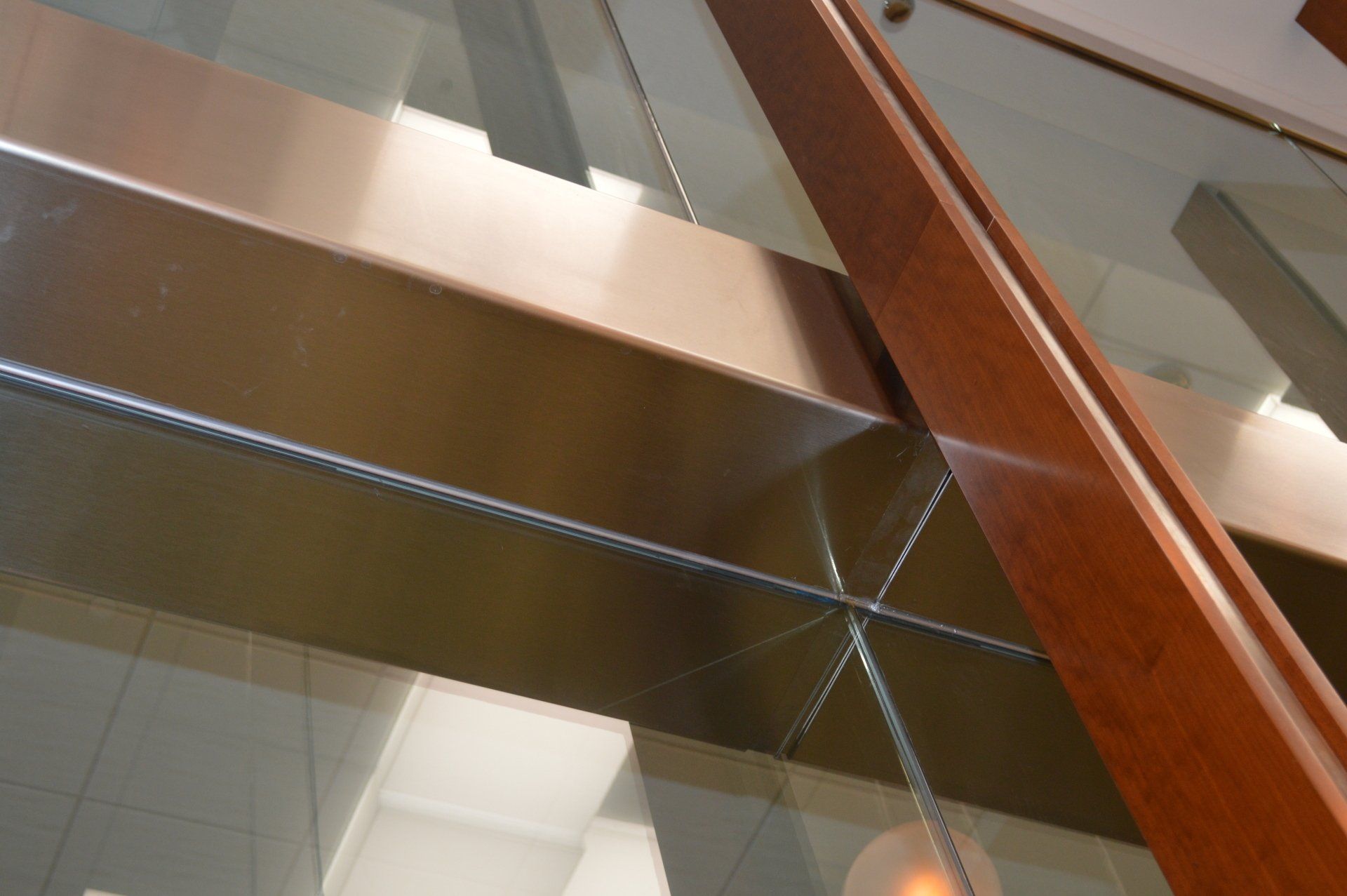 A close up of a glass staircase with a wooden railing