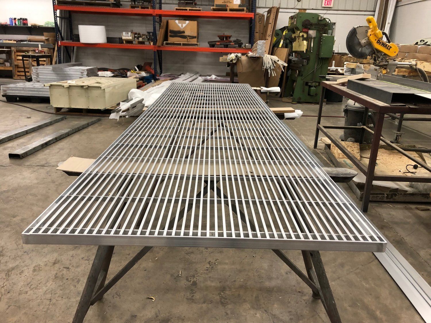 A metal grate is sitting on top of a metal table in a factory.