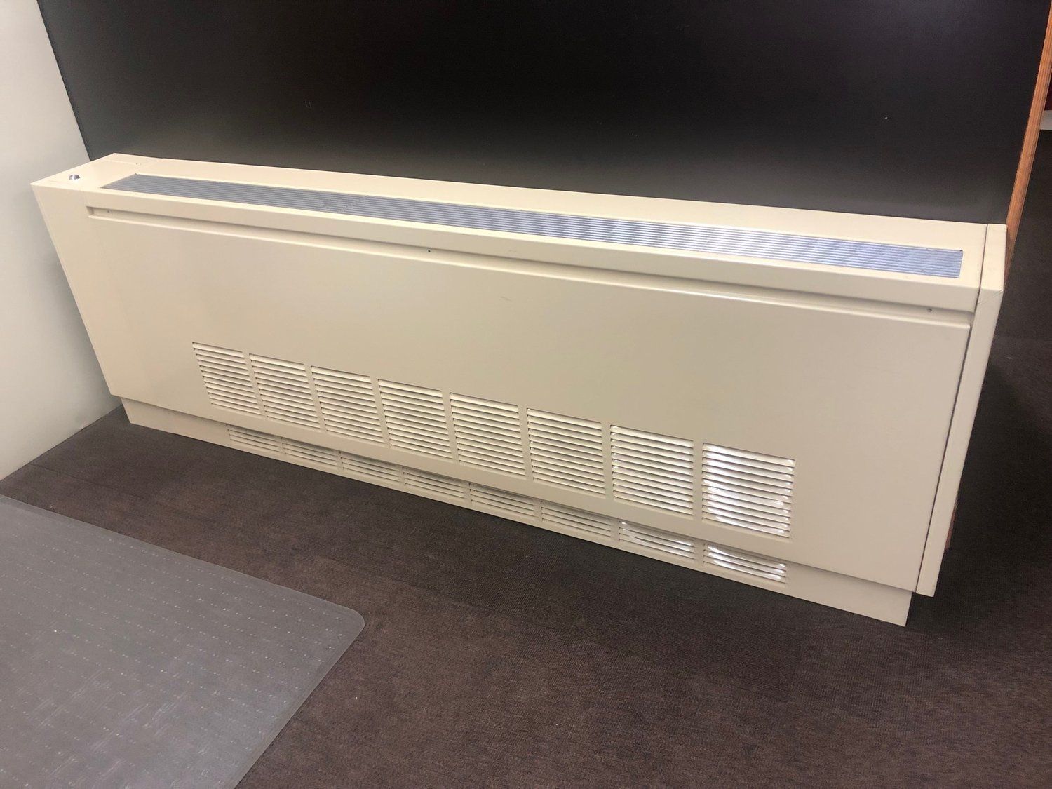 A white radiator is sitting on the floor in a room.