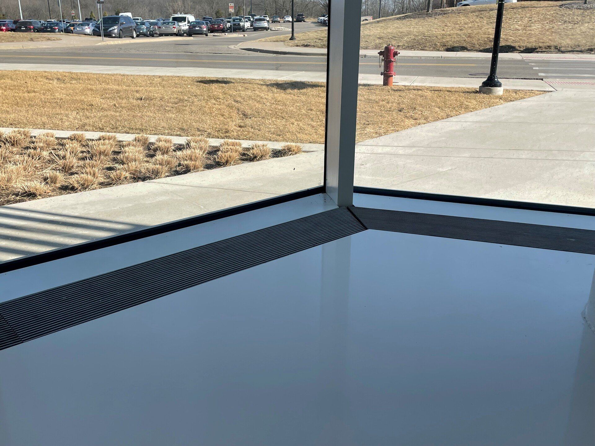 A fire hydrant is visible through a window in a parking lot.