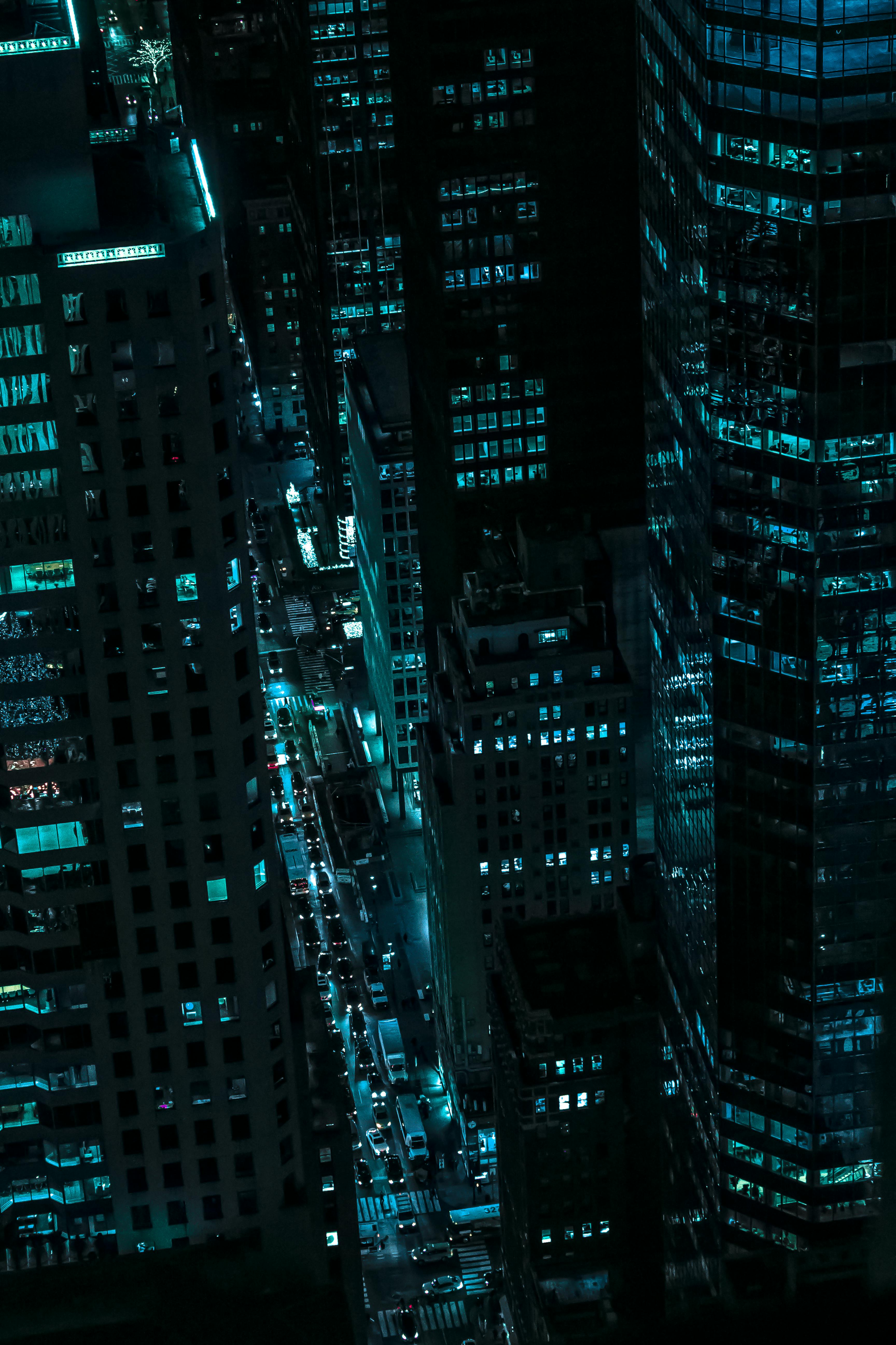 Nighttime cityscape with tall buildings lit by turquoise lights.