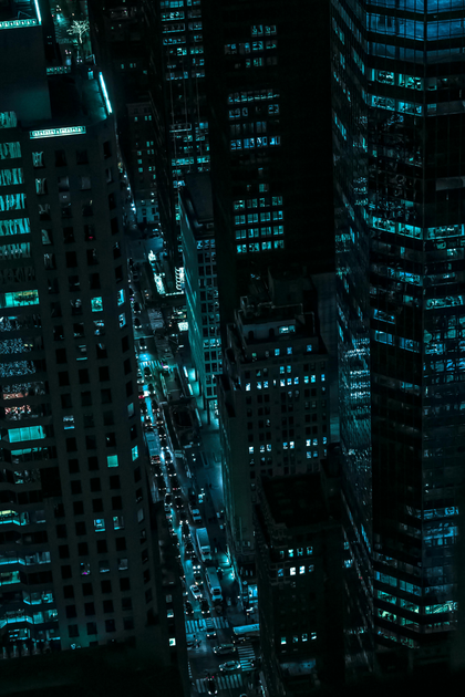 Nighttime cityscape with tall buildings lit by turquoise lights.