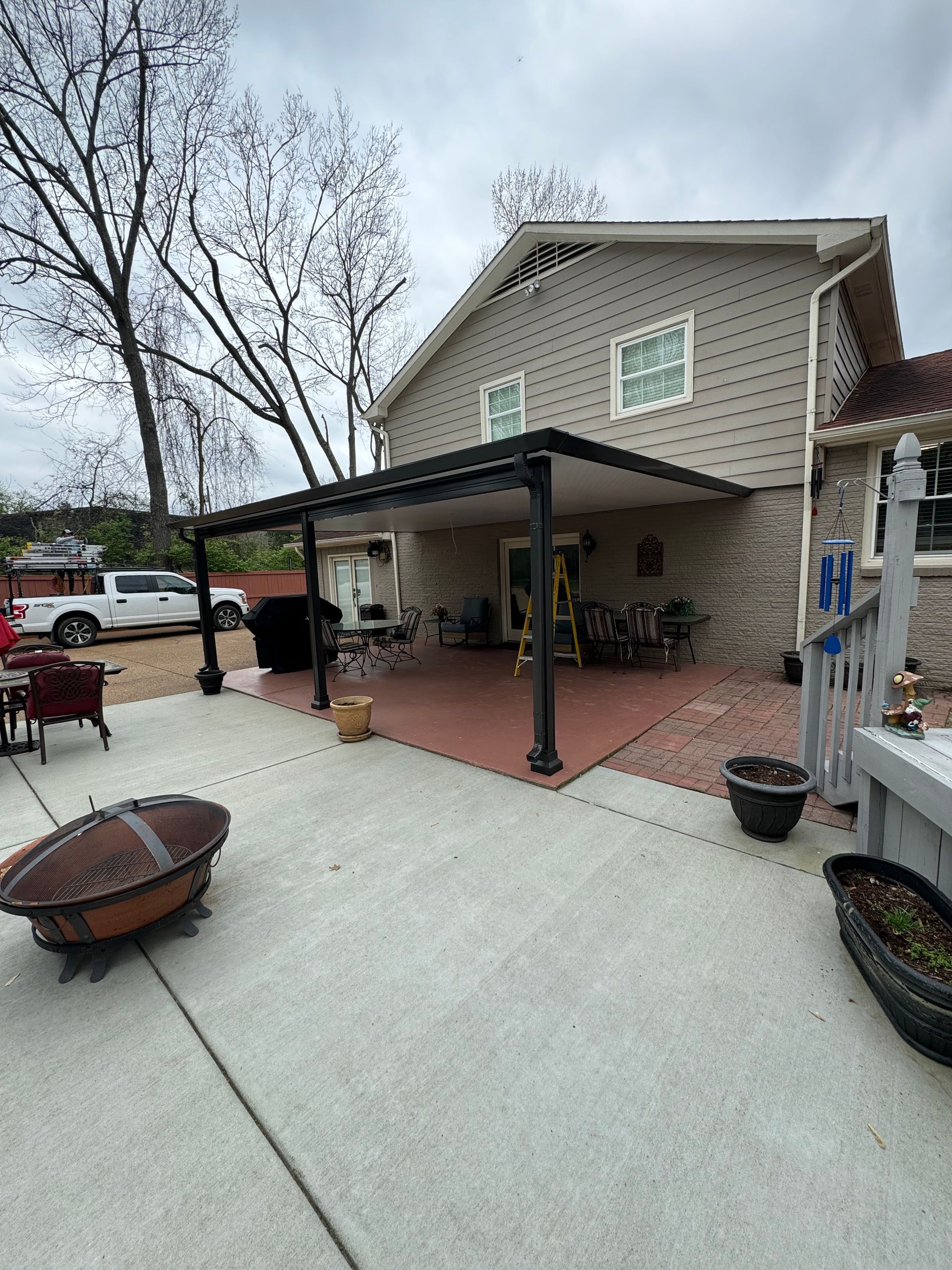 A large house with a covered patio and a fire pit in front of it.