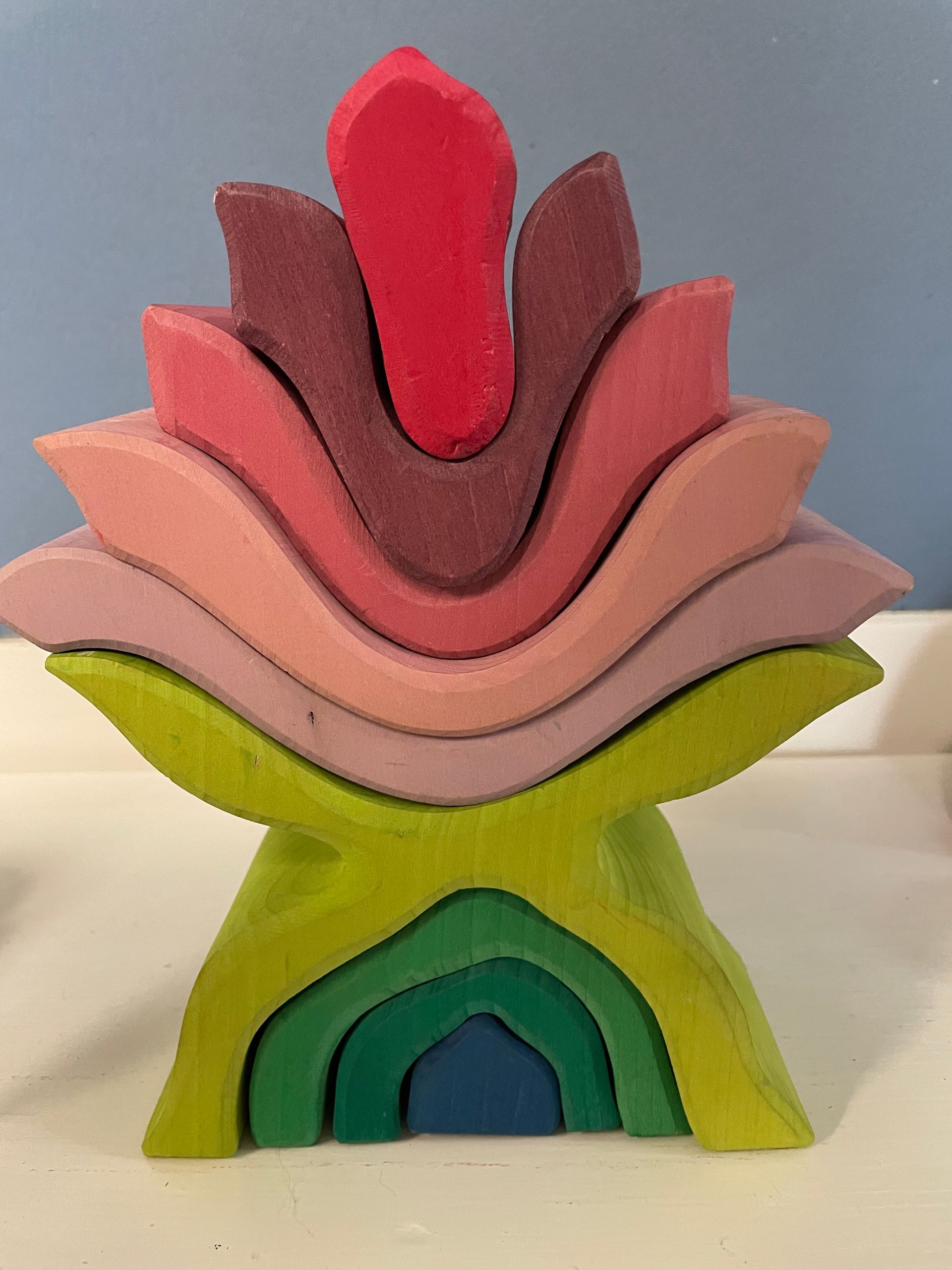 Children and teacher craft around a table in a classroom. Colorful paper and crayons are present.